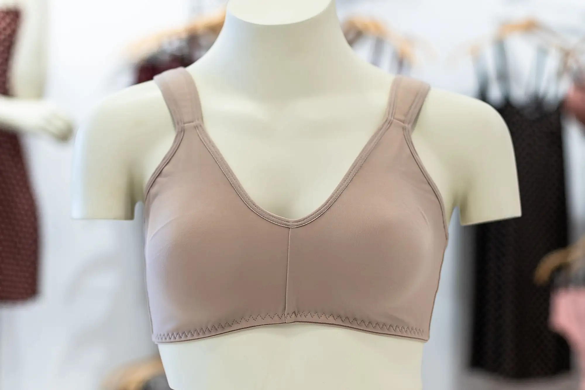 Beige blød bh med hel skål og brede stropper på en hvid udstillingsbuste i en butik