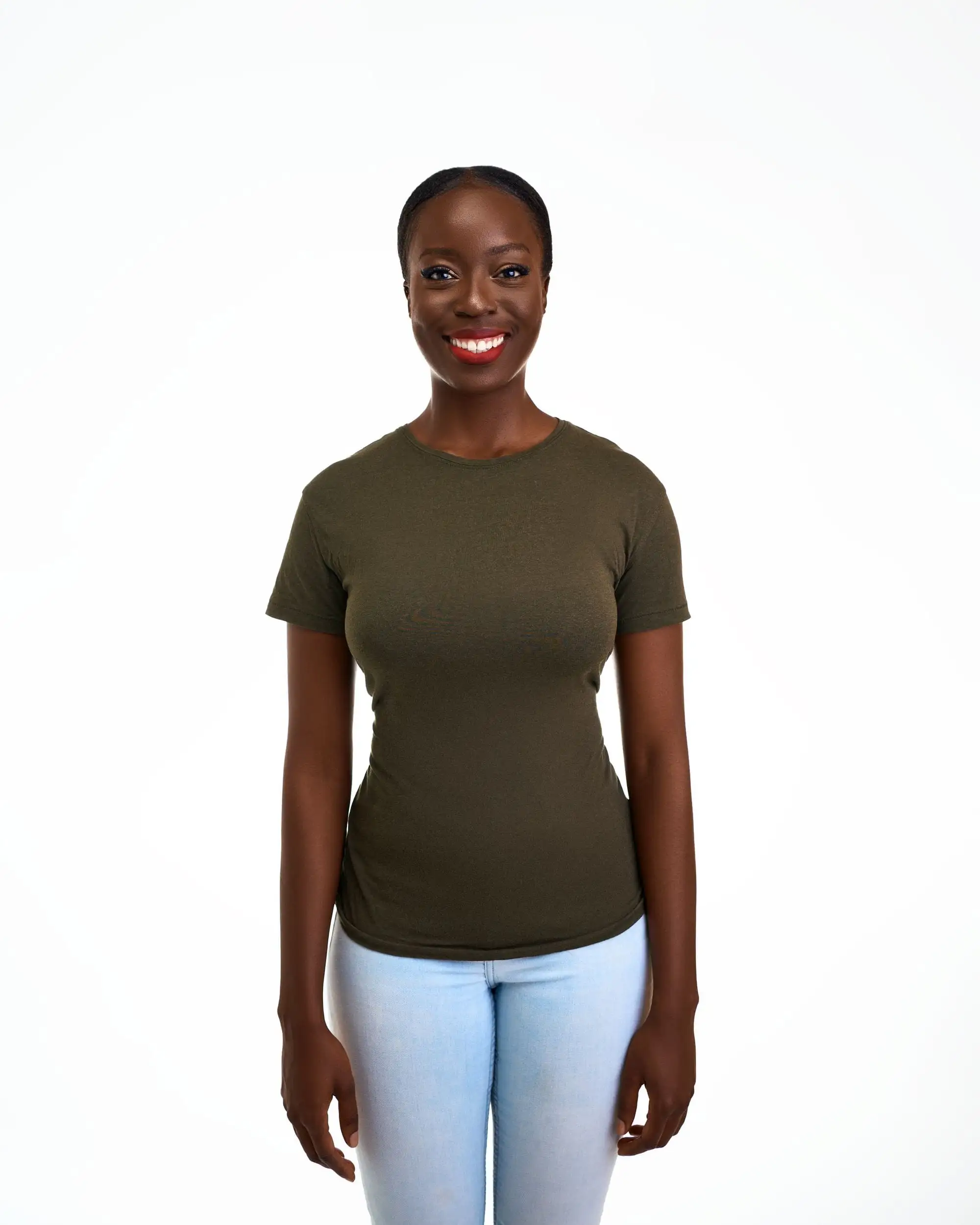 Smilende kvinde i tætsiddende olivengrøn T-shirt og lyse jeans foran en hvid baggrund