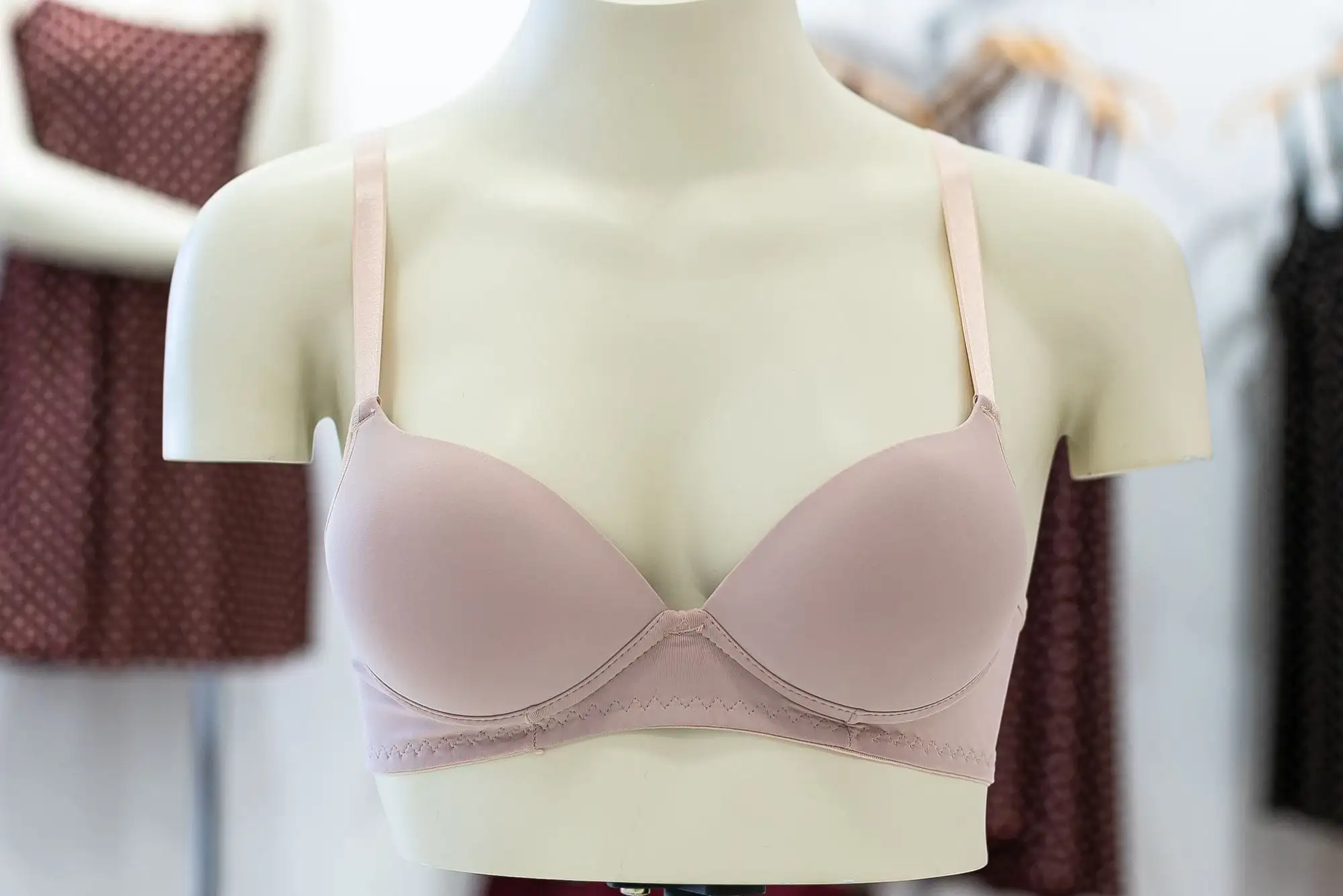 Lyserød vatteret bh med glatte, formstøbte skåle på en hvid udstillingsbuste i en butik